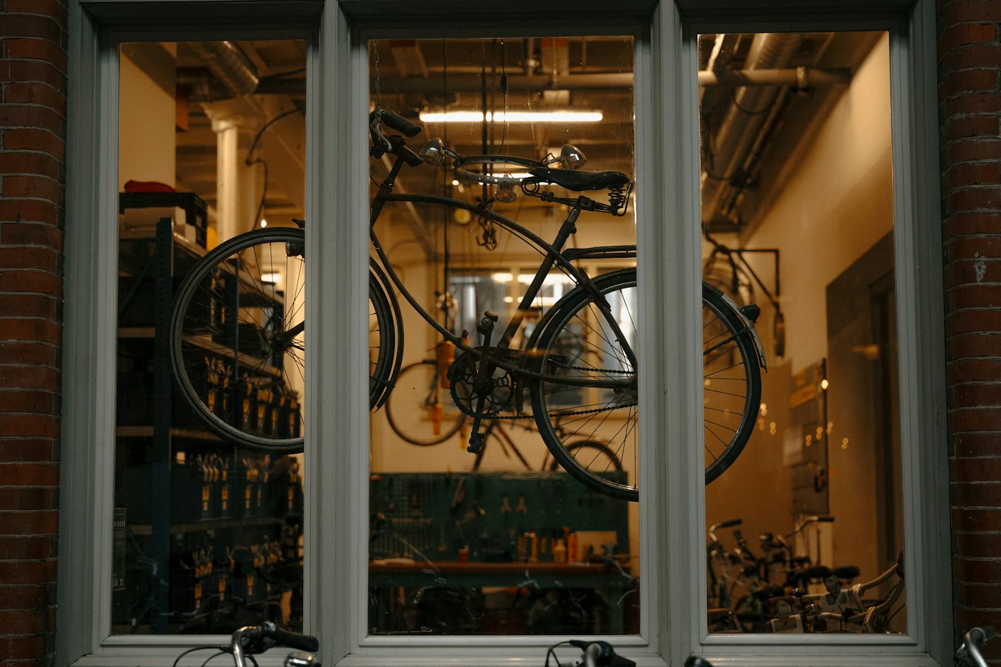 Bicicletta d'epoca in vetrina con attrezzi da riparazione.