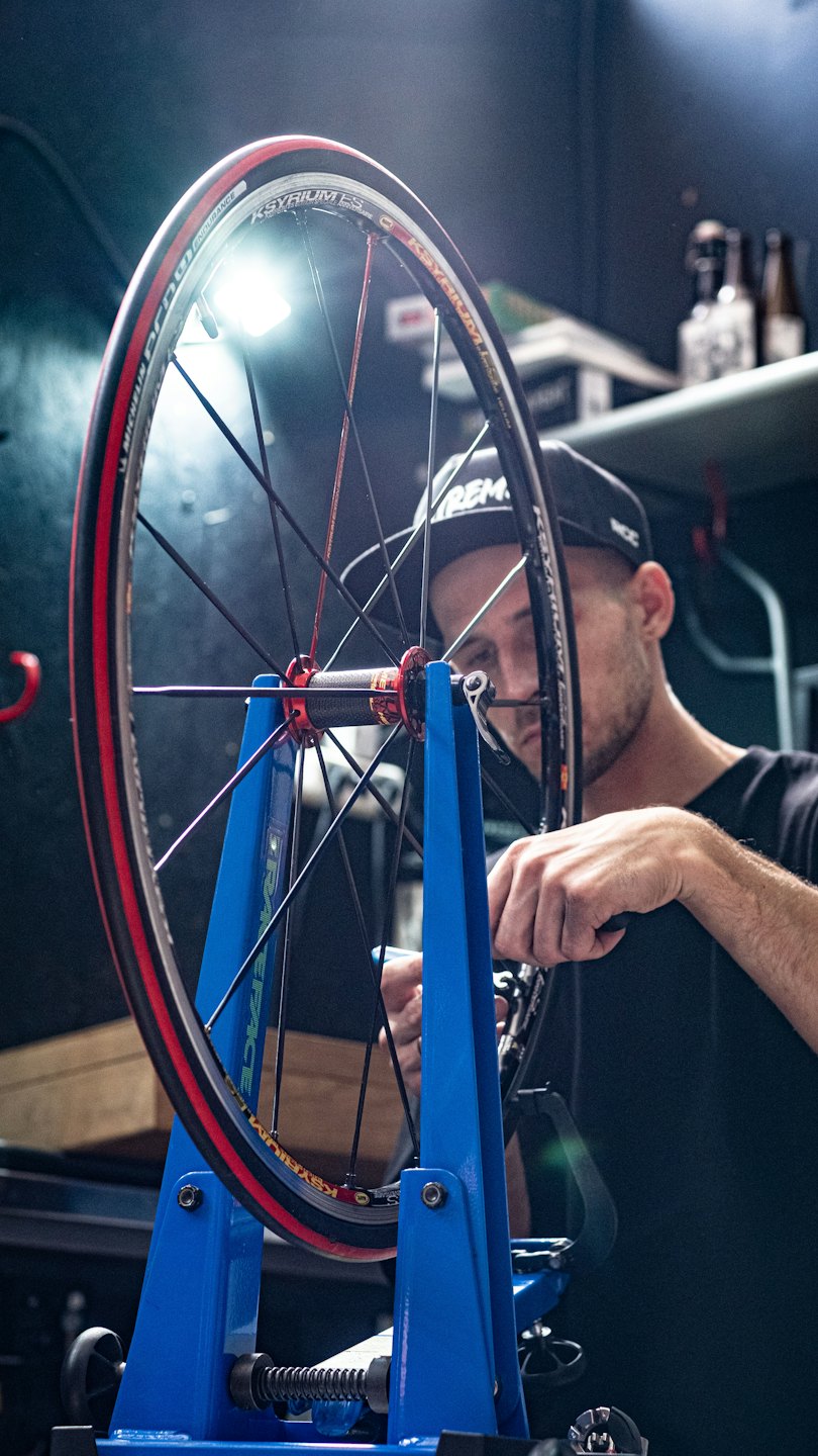 Meccanico che regola la ruota di una bicicletta su un cavalletto di centratura.